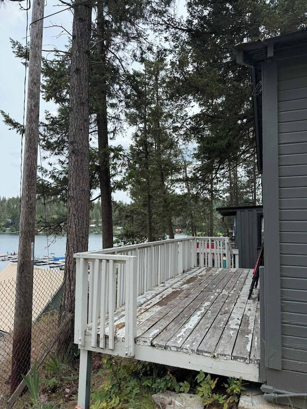 A wooden deck with a railing, a small shed, and a body of water in the background.