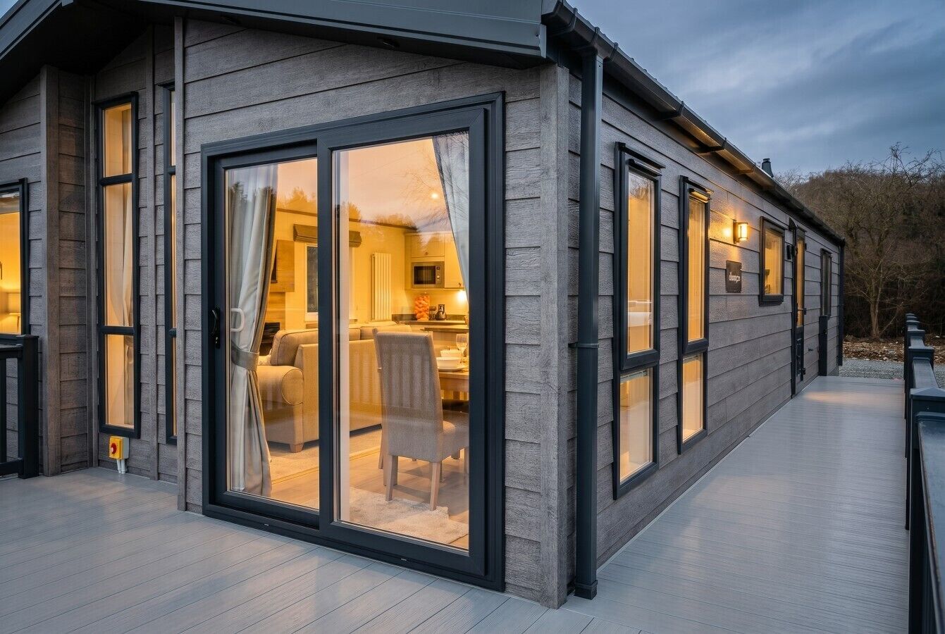 Warm lodge lighting spills onto the deck as evening settles over the park.