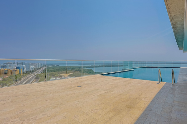 Una piscina en la azotea con vistas despejadas del paisaje urbano y un puente a lo lejos.