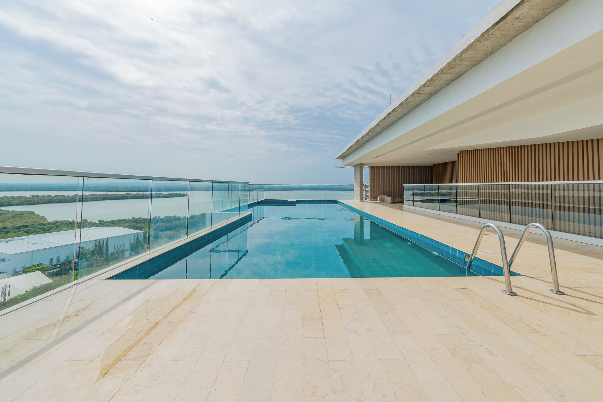 Une piscine à débordement située sur le toit, dotée d’une balustrade en verre, offrant une vue dégagée sur le paysage et présentant un design architectural moderne.