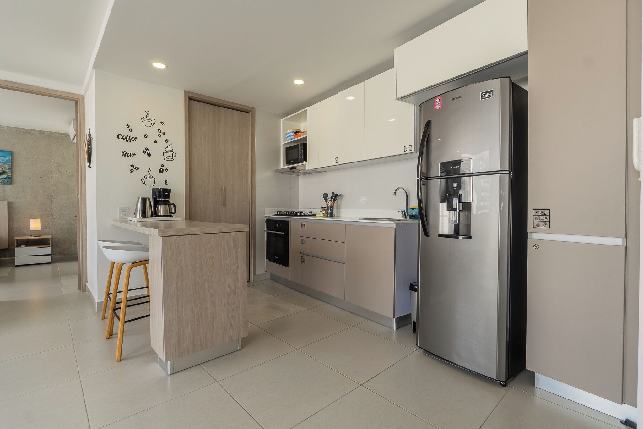 Una cocina moderna con un refrigerador de acero inoxidable, un microondas y una cafetera.