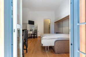 Una camera da letto con un letto, una scrivania con una sedia, una televisione e un armadio.