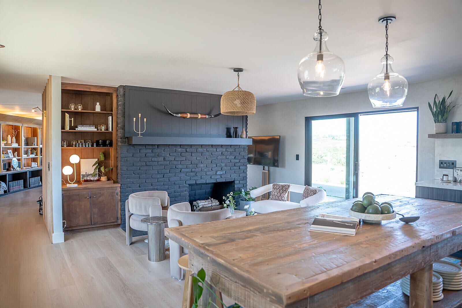 Une cuisine moderne avec un mur en briques, une table à manger en bois et des luminaires suspendus.