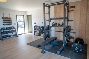 Ein Fitnessraum mit einem Squat-Stand, Kurzhanteln und Gewichtsplatten.