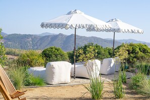 Terrasse mit Sonnenschirmen, ein Holzstuhl und Blick auf Berge.