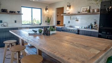 Una cocina con una isla grande, taburetes de bar, estufa y un ventanal amplio.