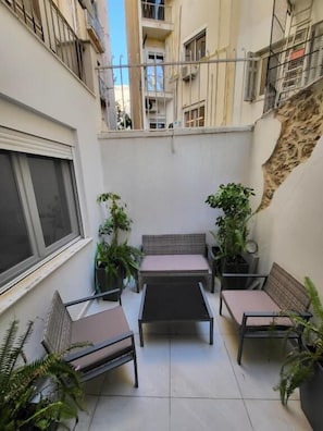 Ein kleiner Balkon mit Sitzgelegenheit, Topfpflanzen und Blick auf angrenzende Gebäude.