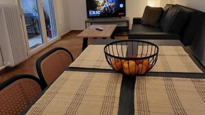 Una sala de estar con televisión, un sofá, una mesa de centro con frutero y un ventanal corredero que da a un espacio exterior.