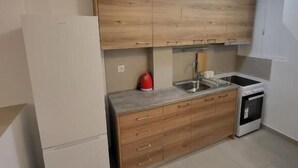 Una cocina funcional con armarios de madera, un refrigerador blanco, un lavamanos y un horno pequeño.