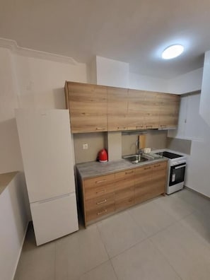 Eine kleine Küche mit Holzausstattung, einem weißen Kühlschrank, einer Spüle und einem kleinen Backofen.