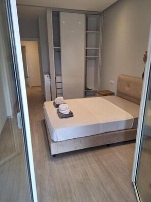 Ein modernes Schlafzimmer mit Bett, Nachttisch, Kleiderschrank und Schiebetürenschrank.