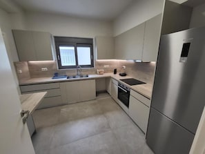 Una cocina moderna con horno empotrado, refrigerador de acero inoxidable y ventana sobre el fregadero.
