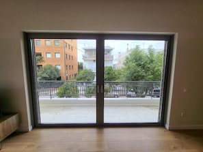 Una habitación con un gran ventanal corredero que da a un espacio exterior con vistas a edificios y árboles.