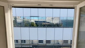 Een kamer met een grote schuifglazen deur die uitkomt op een balkon met uitzicht op gebouwen.