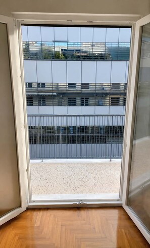 A room with a large sliding glass door leading to a balcony with a view of buildings. - Boutique 1 Bd Stay in Mavili Square Athens (Athina)