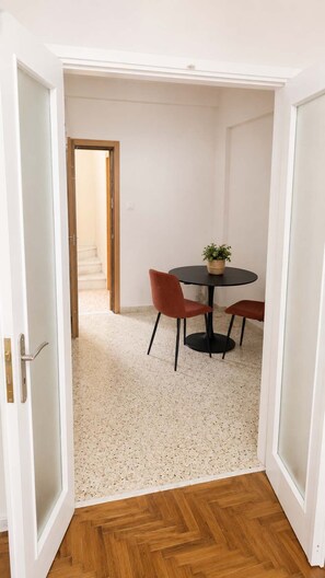 A room with a round table, two chairs, a potted plant, and a wooden floor. - Boutique 1 Bd Stay in Mavili Square Athens (Athina)