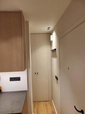 A hallway with a wooden cabinet, a door, and a light fixture. - Cozy Studio Kolonaki (Athina)