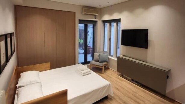 Een moderne hotelkamer met een houten bed, een bureau, een stoel, een televisie en een raam.
