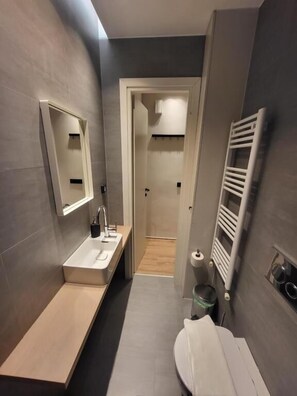 Ein modernes Badezimmer mit integriertem Waschbecken, Spiegel und Handtuchhalter.