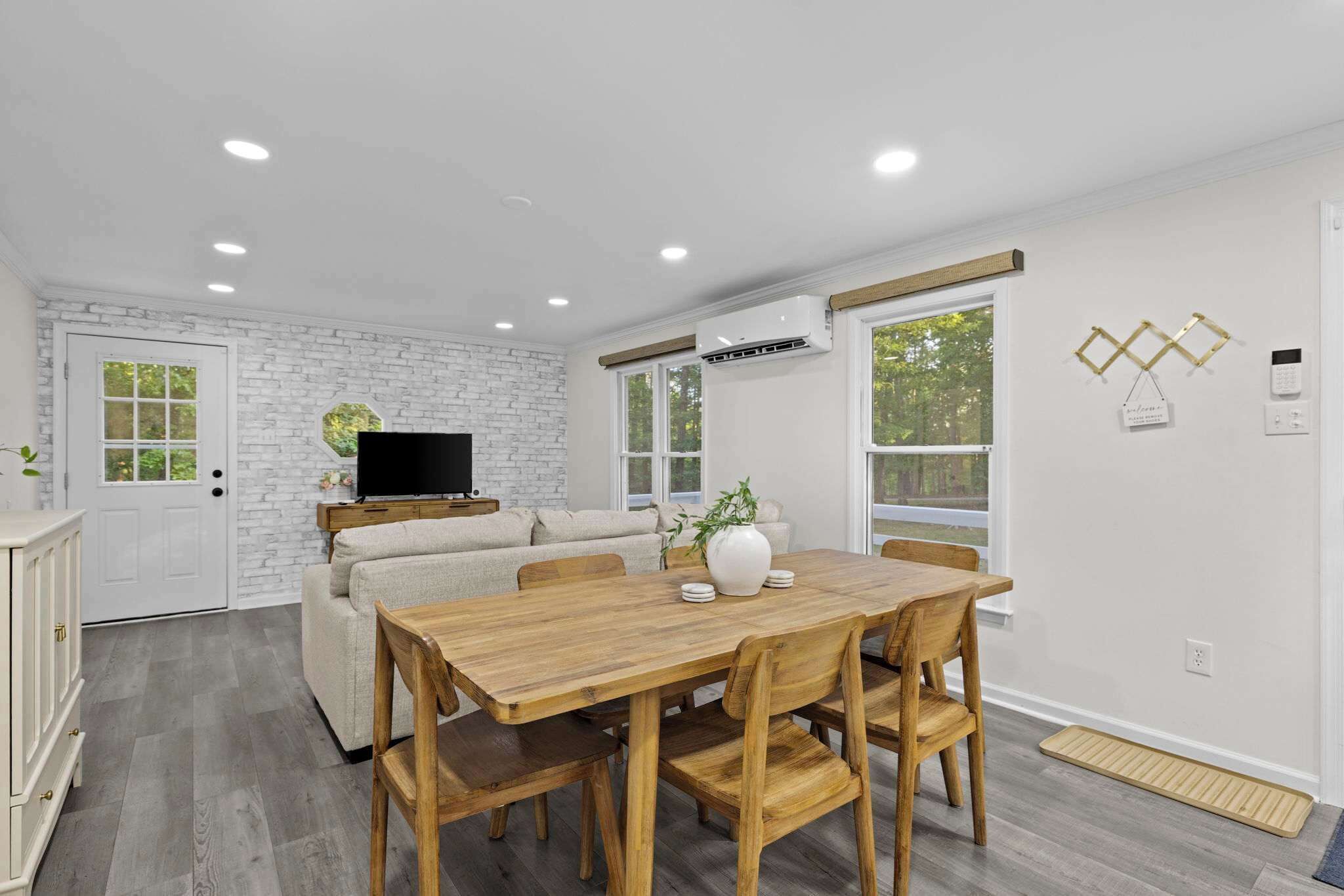 Una sala moderna con una mesa de comedor de madera, sofá y televisor.