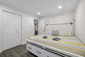 A bedroom with a bed, bedside tables, a wardrobe, and a door.
