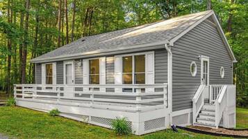 A single-story cabin with a porch, surrounded by trees.
