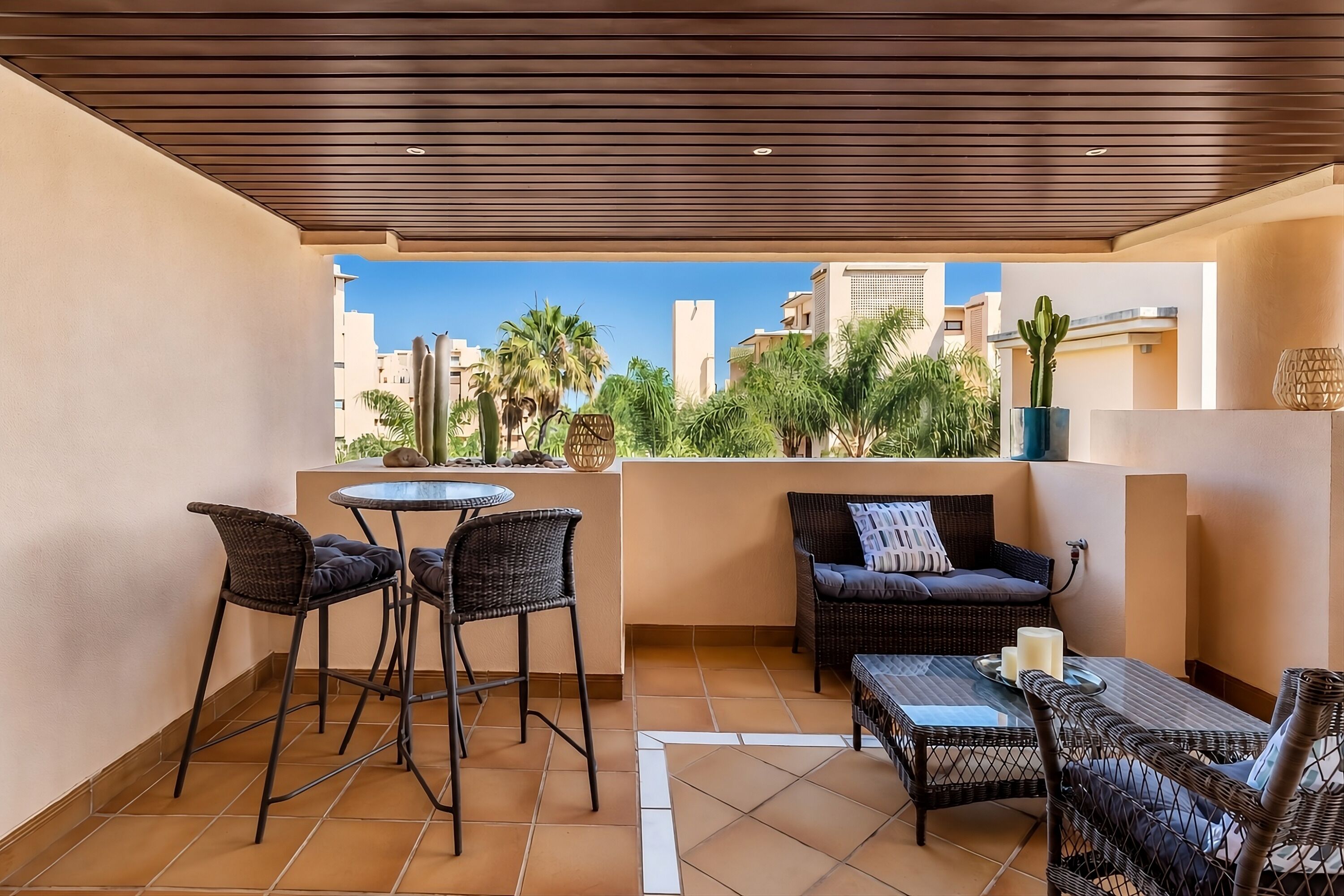 A balcony with a table and chairs, a sofa, and a cactus plant.