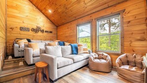 Ein gemütliches Blockhaus-Interieur mit einer Couch, zwei Sitzsäcken und einem kleinen Tisch.