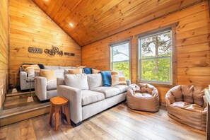 A cozy cabin interior with a sofa, two bean bags, and a small table. - 🏔️ Redtail Horizon | Indoor Pool, Hot Tub + Mountain Views🏔️ (Sevierville)