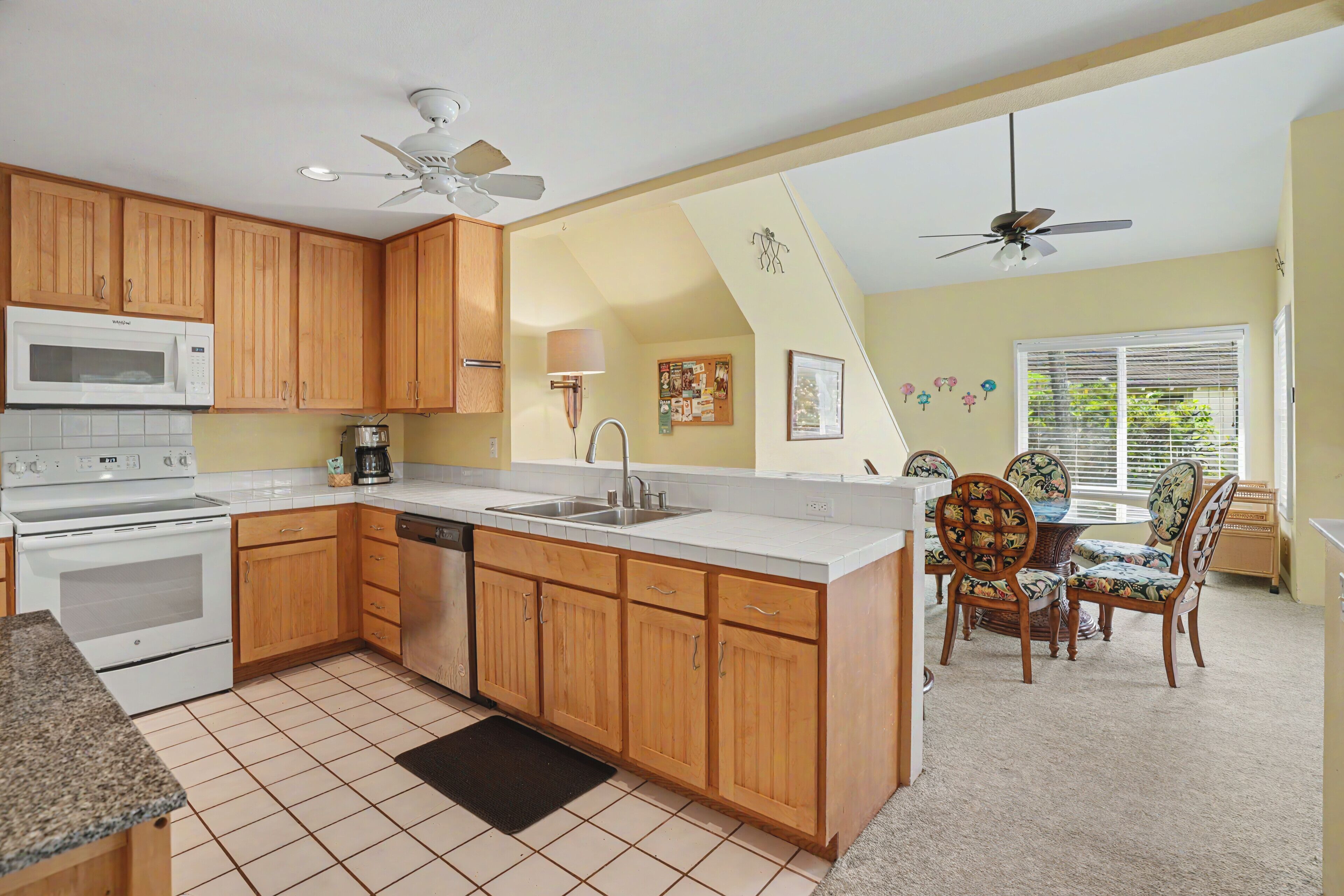 A kitchen with wooden cabinets, a microwave, stove, and a dining area with chairs.
