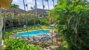 Une piscine entourée de palmiers et une terrasse délimitée par une clôture.