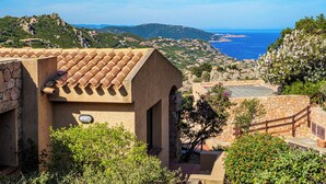 Un edificio de estilo mediterráneo, con tejados de tejas rojas, paredes de piedra y vistas al mar y a las colinas.