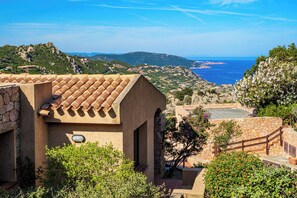A Mediterranean-style building with terracotta roof tiles, stone walls, and a view of the sea and hills. - Solo Amore 1  - villa in Costa Paradiso Sardinia residential complex with a pool (Costa Paradiso)