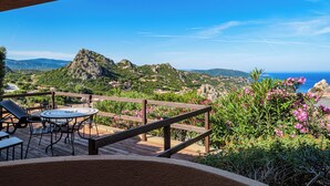 Una terraza con mesa y sillas, con vistas a un paisaje montañoso y al mar.