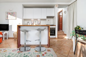 Eine moderne Küche mit weißen Schränken, einem eingebauten Backofen und zwei Barhocker.