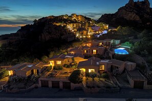 A coastal resort with multiple buildings, a swimming pool, and a rocky hillside backdrop. - Solo Amore 1  - villa in Costa Paradiso Sardinia residential complex with a pool (Costa Paradiso)