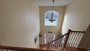 A staircase with wooden railings and white balusters leading to a landing. - New- Spacious 4-bedroom Winter Rental Home with Fireplace in Wells, Maine (Wells)