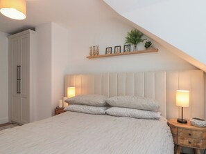 Ein Schlafzimmer mit einem Bett, Nachttischlampen, einem Nachttisch, einem Kleiderschrank und einem Regal mit Dekoration.