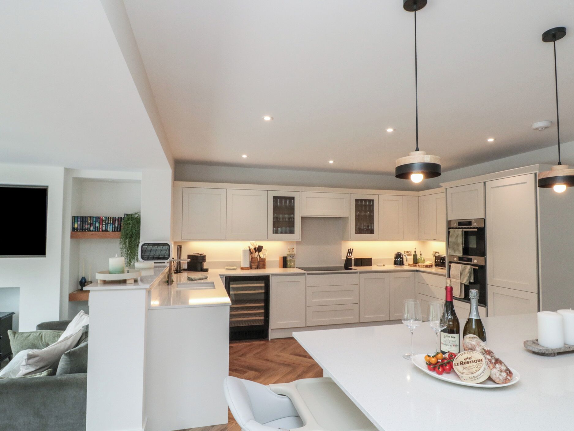 Una cocina moderna con armarios blancos, una isla central e iluminación colgante.