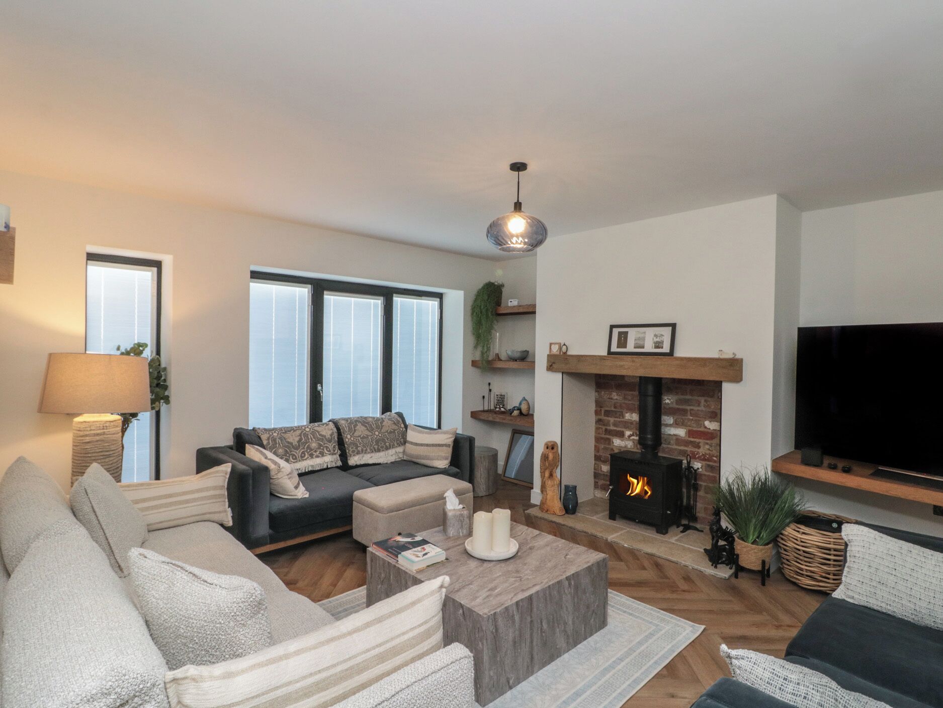 A living room with a sofa, coffee table, fireplace, TV, and large windows.