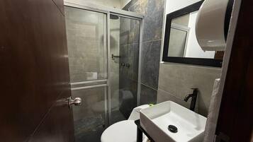 Un baño con ducha, inodoro y lavamanos.