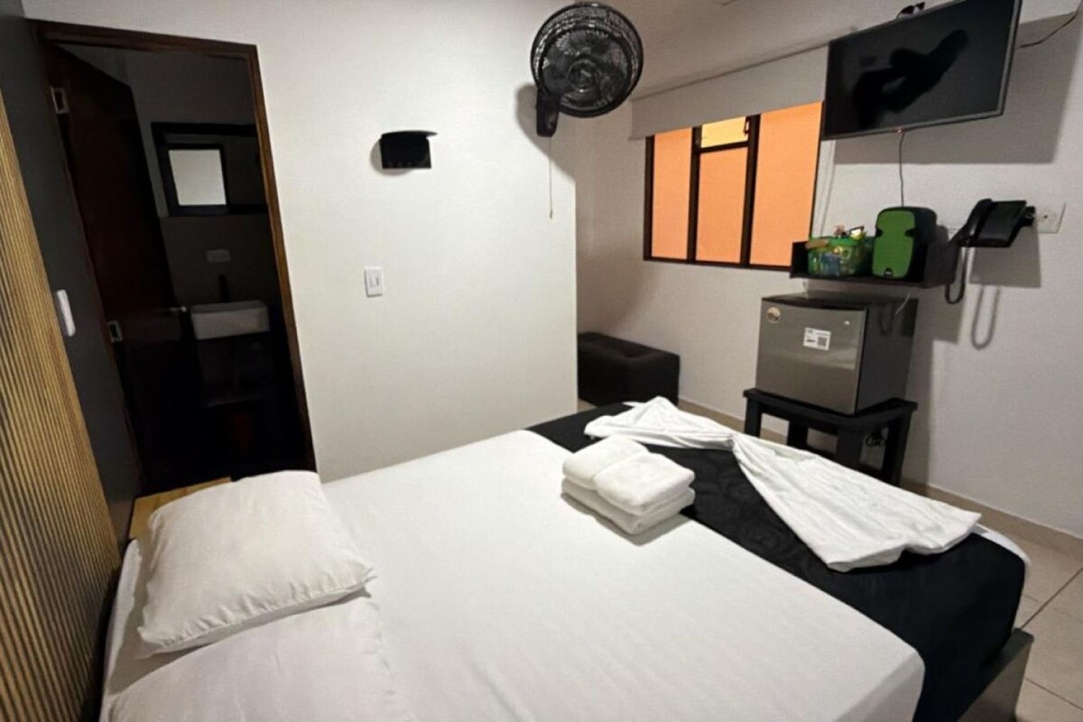 Une chambre d’hôtel équipée d’un lit, d’un bureau, d’un téléphone et d’un petit réfrigérateur.