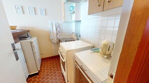 Eine kleine Küche mit Spüle, Wasserkocher und Kühlschrank.