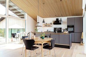A modern kitchen with a central island, black chairs, and a dining table. - Architect-designed gem with views of Venø Bay (Vinderup)