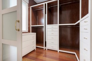 Ein begehbarer Kleiderschrank mit Spiegel, mehreren Schubladen und Holzboden.