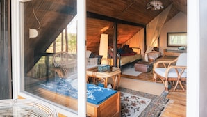 Una habitación acogedora con cama, muebles de mimbre, una ventana y un televisor.