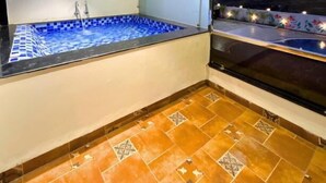 A room with a bathtub, a window with a view, and a tiled floor. - Serene-Restaurant Rooms and Banquet (Indore)