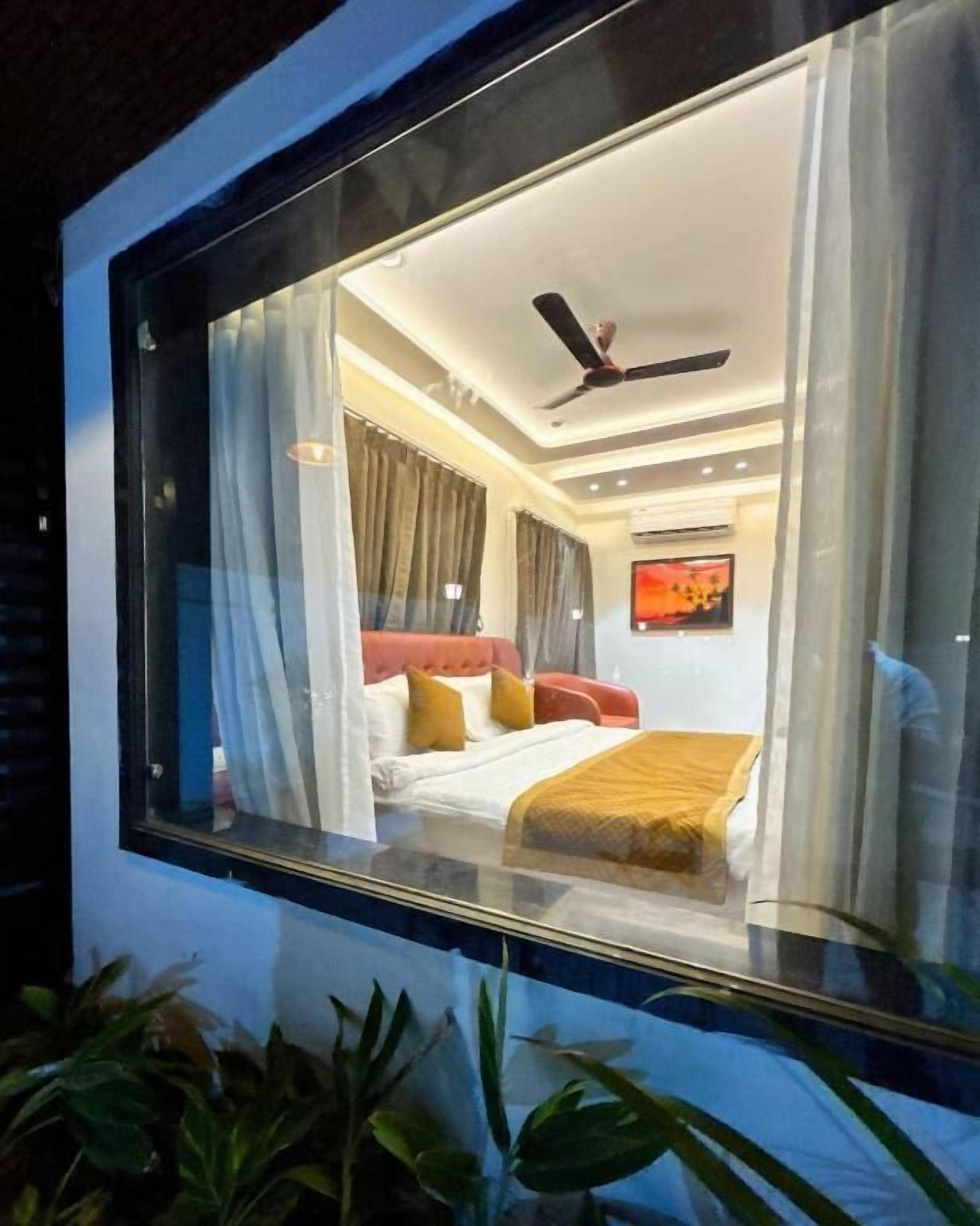 Un dormitorio con cama, cortinas, ventilador de techo y ventana.