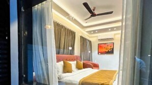 A bedroom with a bed, curtains, a ceiling fan, and a window. - Serene-Restaurant Rooms and Banquet (Indore)
