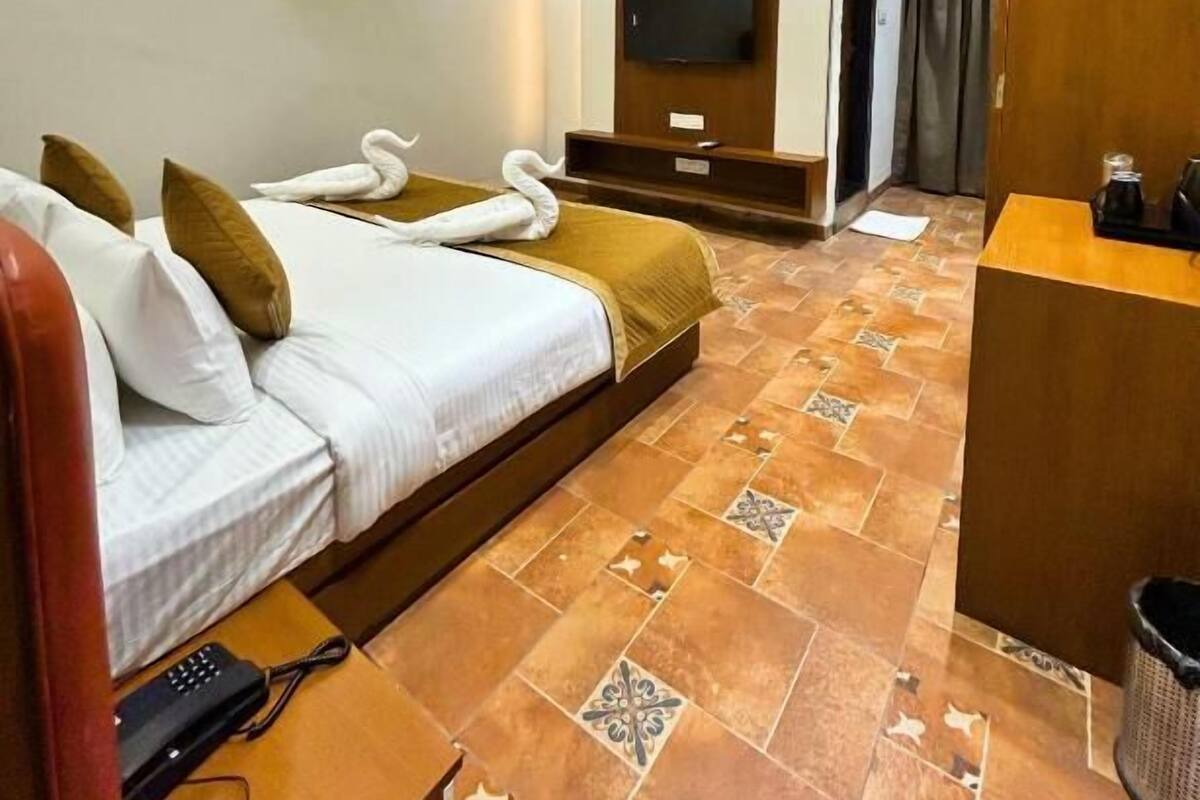 Habitación de hotel con dos camas, televisión, ventilador de techo, aire acondicionado y mostrador de recepción.